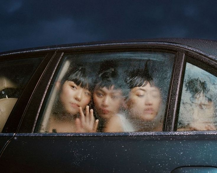Three women pressed up against the foggy glass of a car window