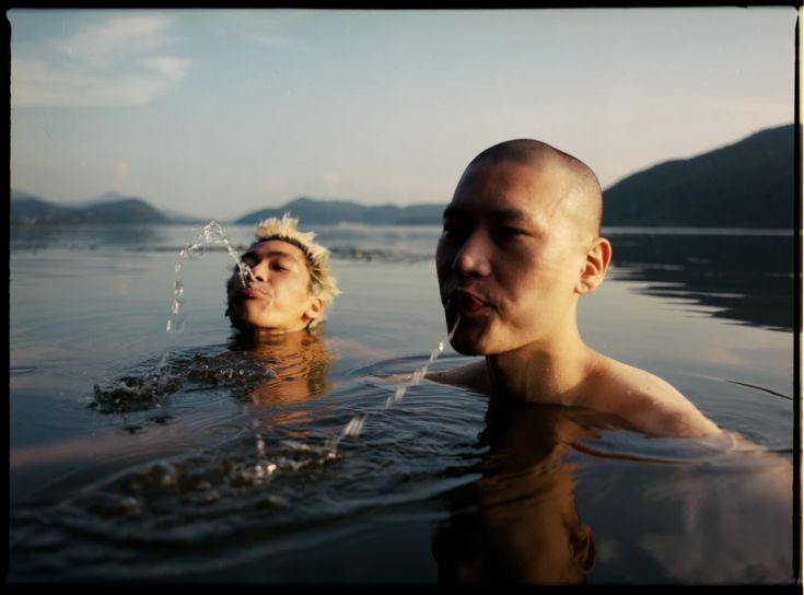 Two Men in a lake, shooting water out of their mouths